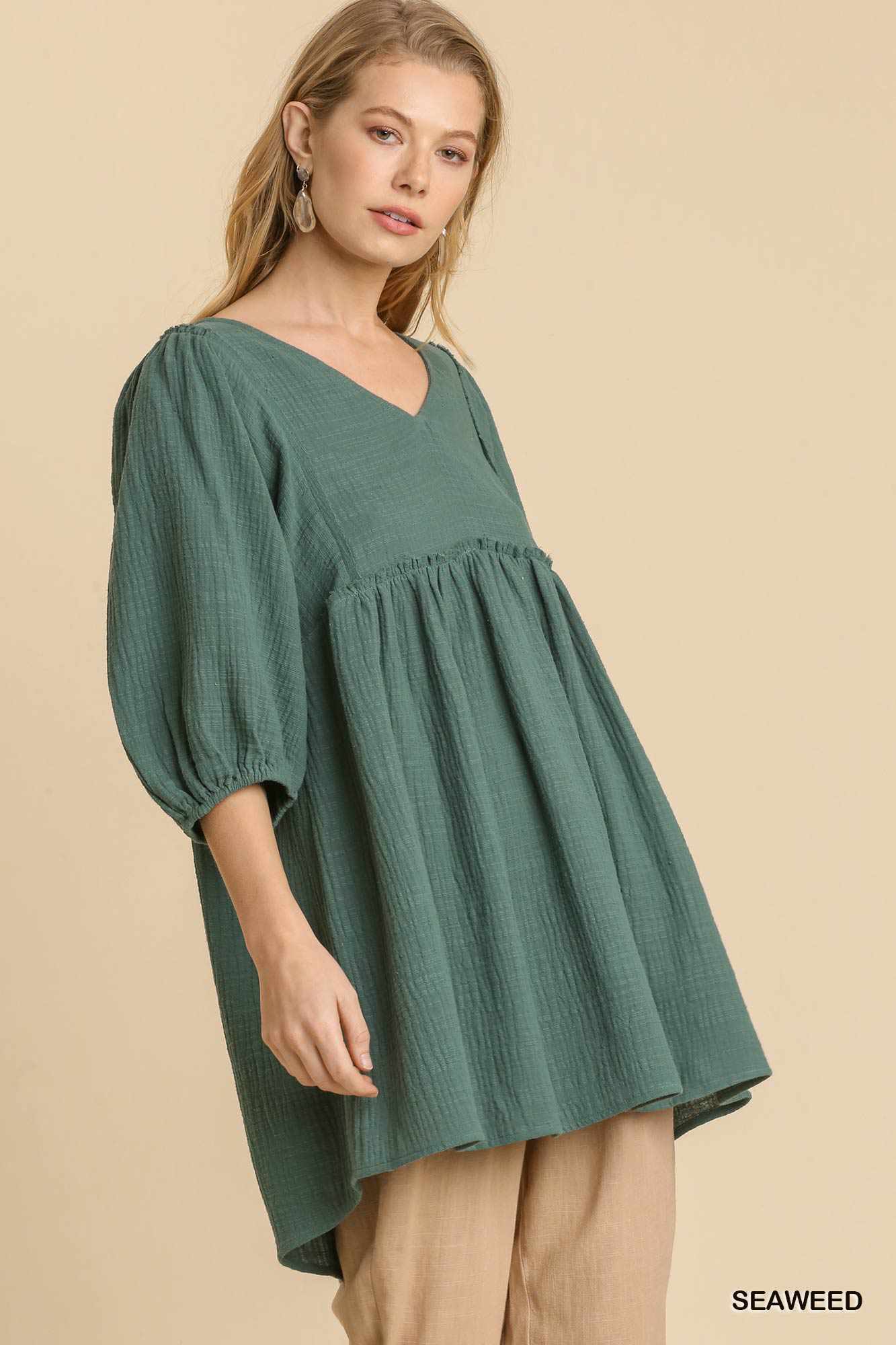 Woman wearing a seaweed green gauze slub V-neck tunic dress with frayed edge detail, showcasing casual and comfortable fashion.