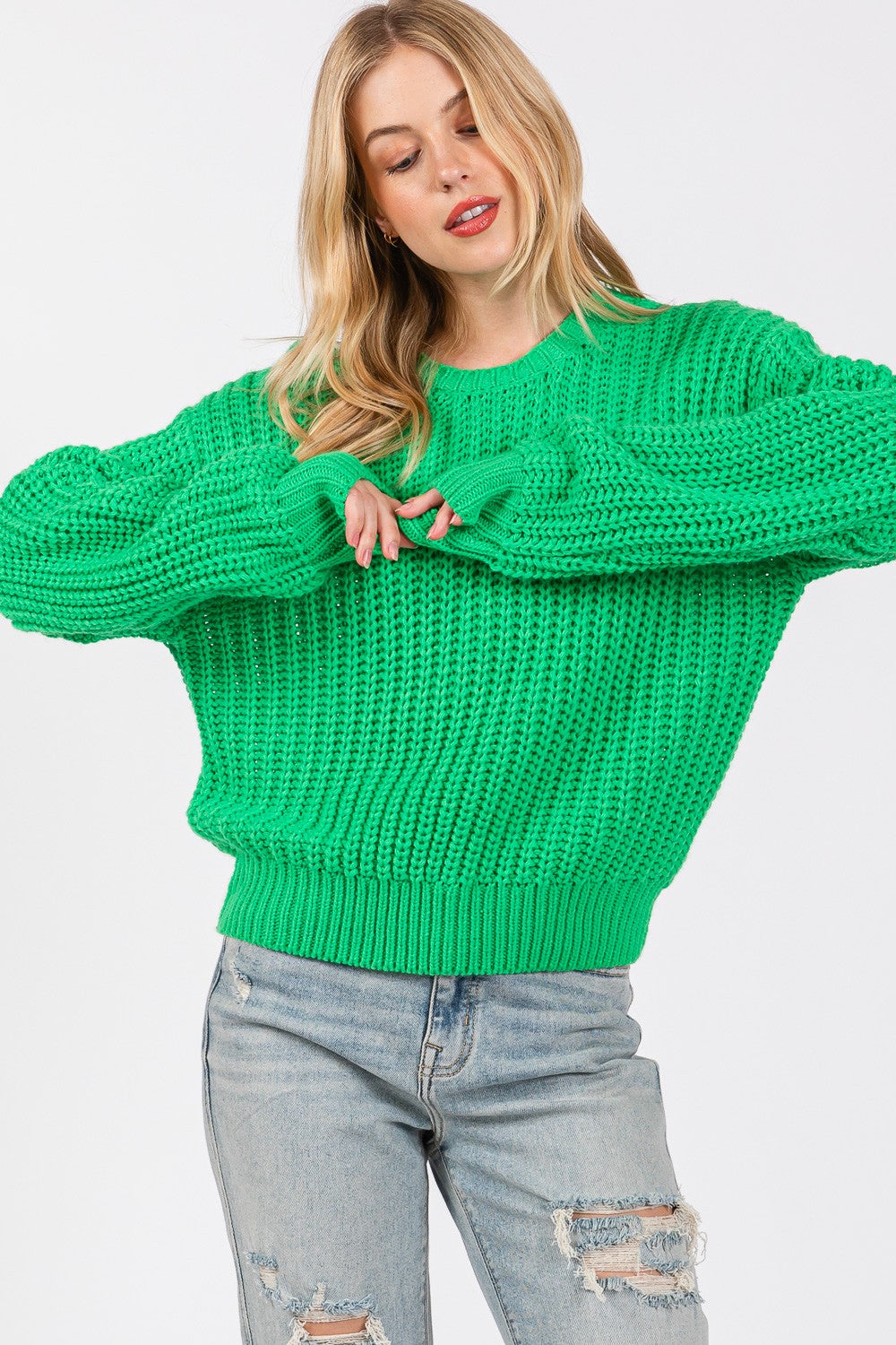 Woman wearing green round neck drop shoulder sweater made of 100% acrylic, showcasing slightly stretchy basic style design.