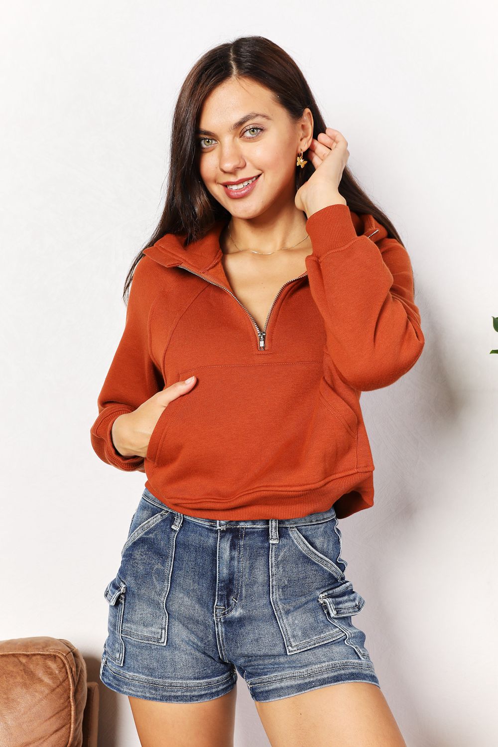 Woman wearing chic half-zip long sleeve hoodie with collared neck, solid pattern, and raglan sleeves, paired with denim shorts.