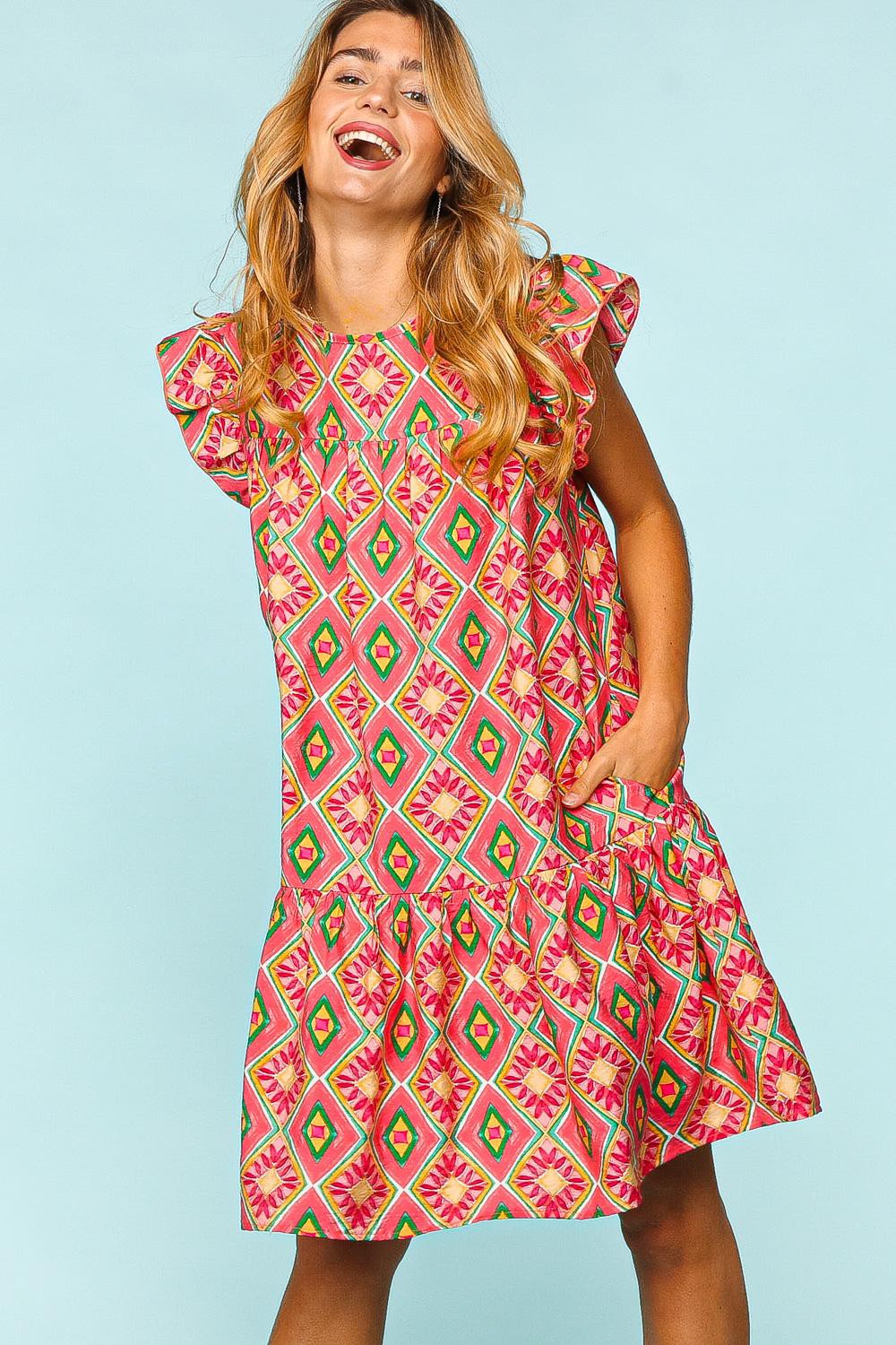 Woman wearing a full-size ruffled printed dress with side pockets, showcasing vibrant colors and playful geometric patterns.