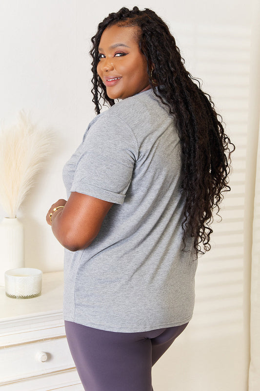 Woman wearing a gray heart graphic cuffed short sleeve t-shirt, showcasing its comfortable fit and stylish design.