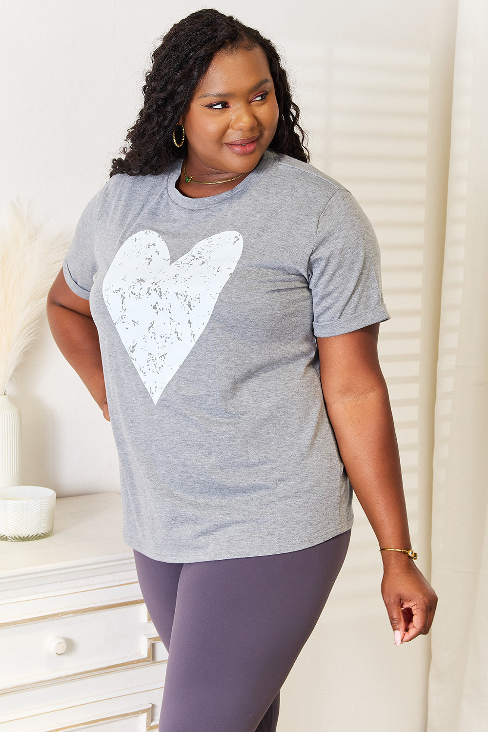 Woman wearing a grey heart graphic cuffed short sleeve T-shirt, perfect for casual and dressy outfits.