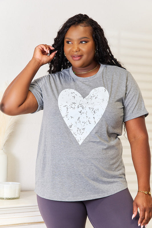 Woman wearing a gray heart graphic cuffed short sleeve t-shirt with a relaxed fit.