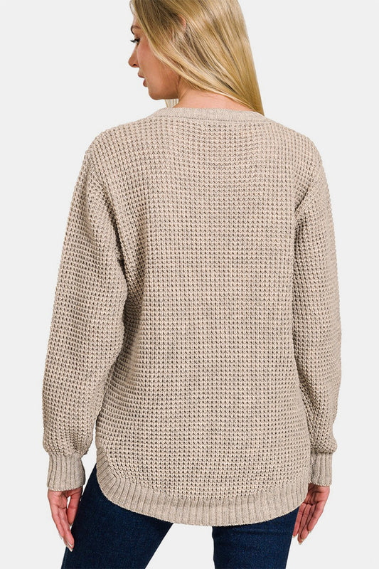 Woman wearing beige high low long sleeve waffle sweater with moderate stretch, viewed from the back.