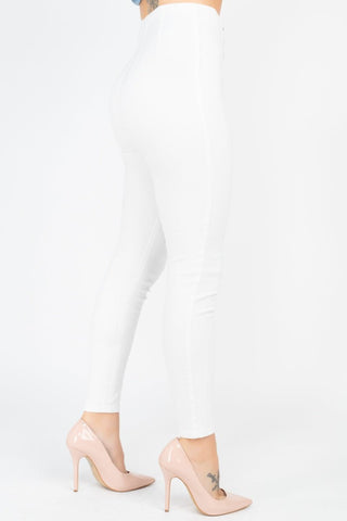 White high waist denim jeans with skinny leg fit and front o-ring zipper, worn with nude high heels.