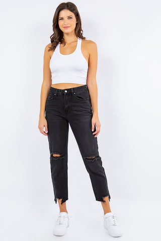 Woman modeling high waist distressed cropped straight jeans with a white tank top and sneakers.