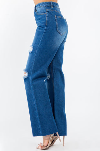High waist distressed wide leg jeans with raw hem, 100% cotton, versatile wash, model wearing heels showcasing trendy denim style.