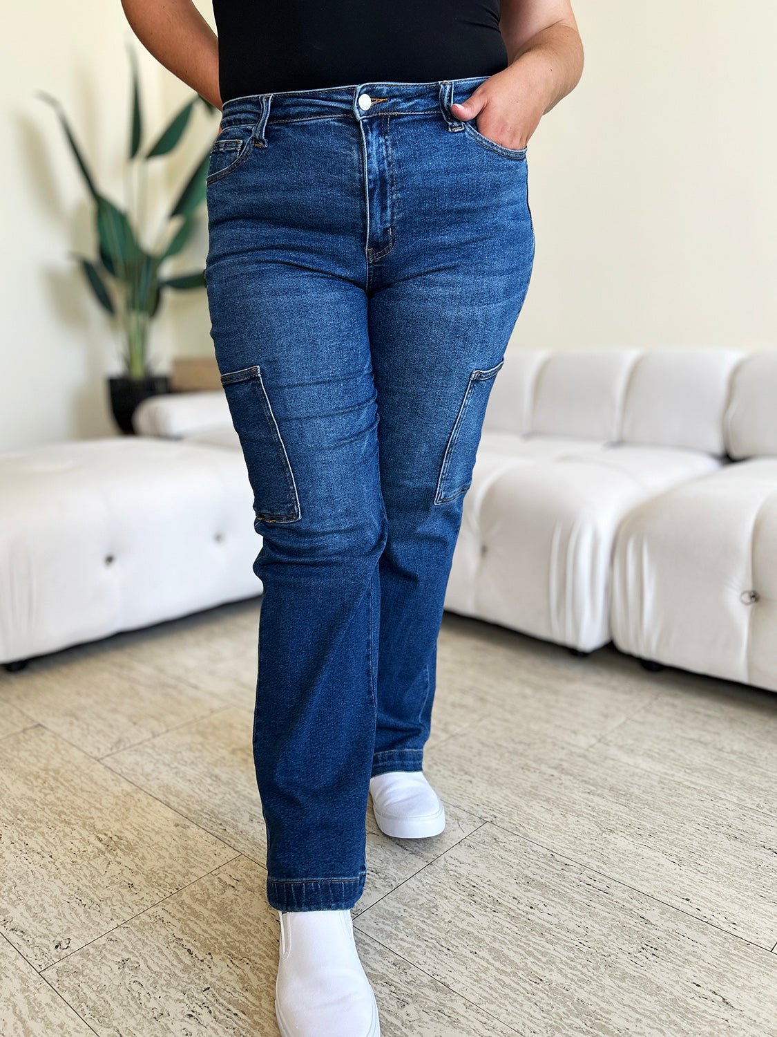 Woman wearing high waist straight cargo jeans with pockets, slightly stretchy denim, in a stylish casual setting.