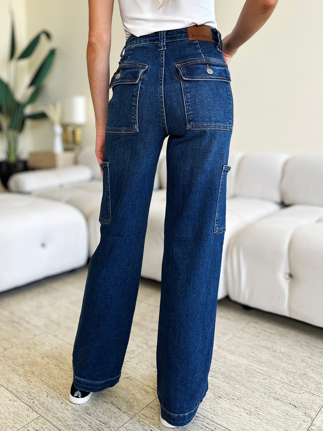 Woman wearing high waist straight cargo jeans with pockets in a stylish living room setting.