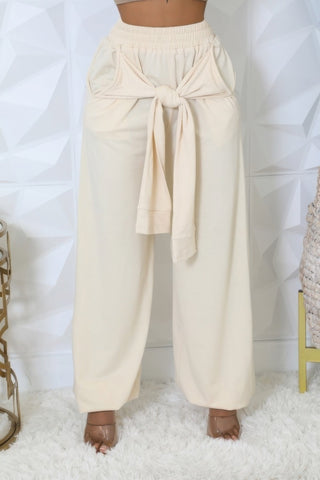 High-waisted cream pants with elastic waistband, practical pockets, and stylish tie detail, perfect for versatile and trendy outfits.