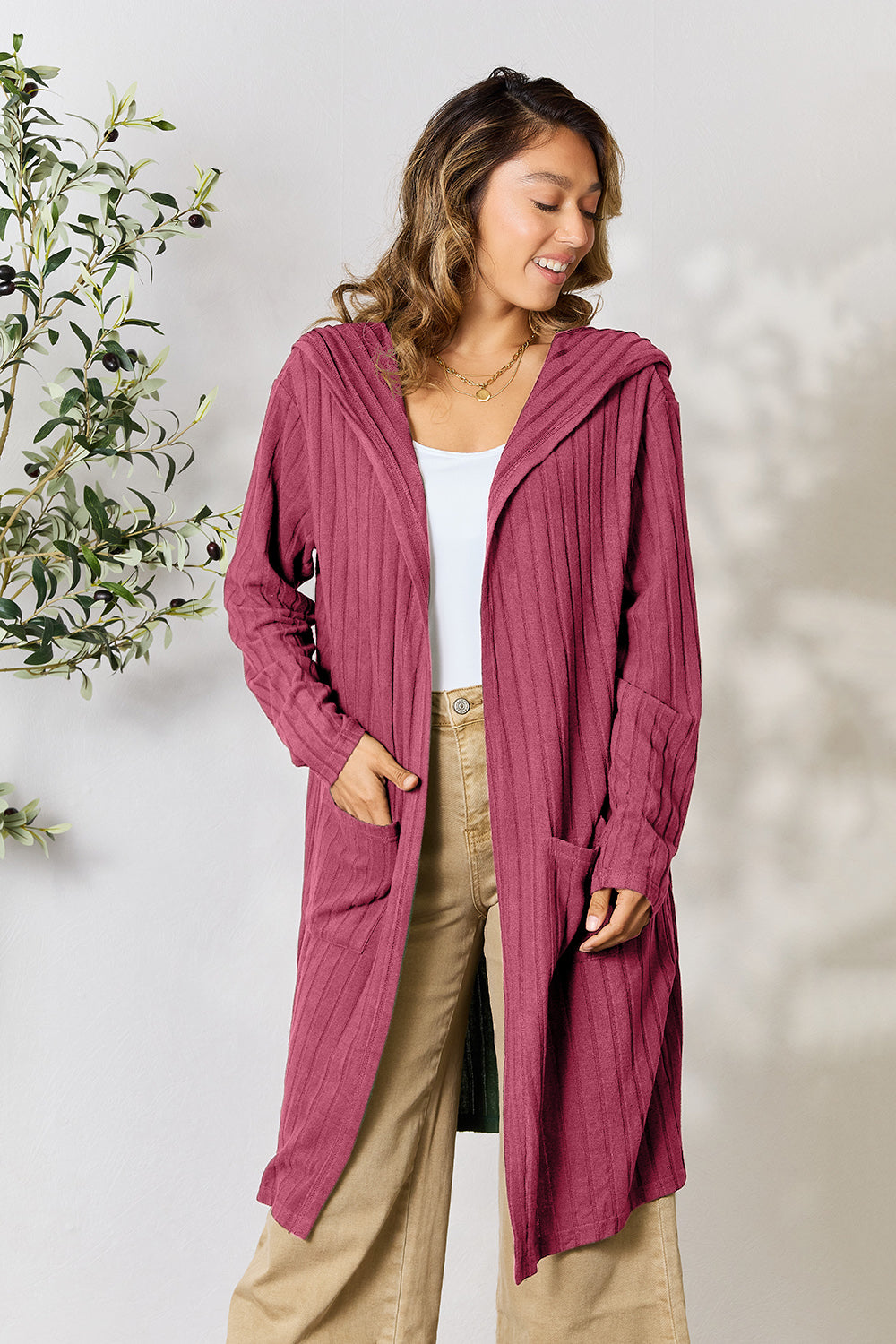 Woman wearing a pocketed hooded sweater cardigan in burgundy, featuring a slightly stretchy, opaque design with full-size length.