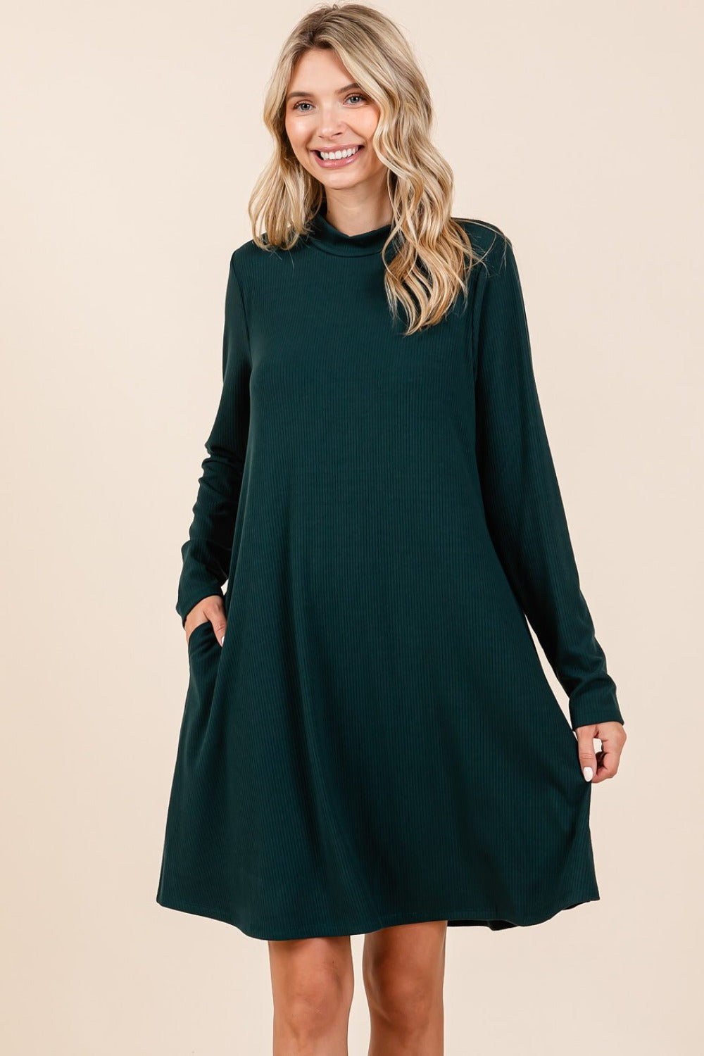 Woman wearing hunter green mock neck long sleeve dress with pockets