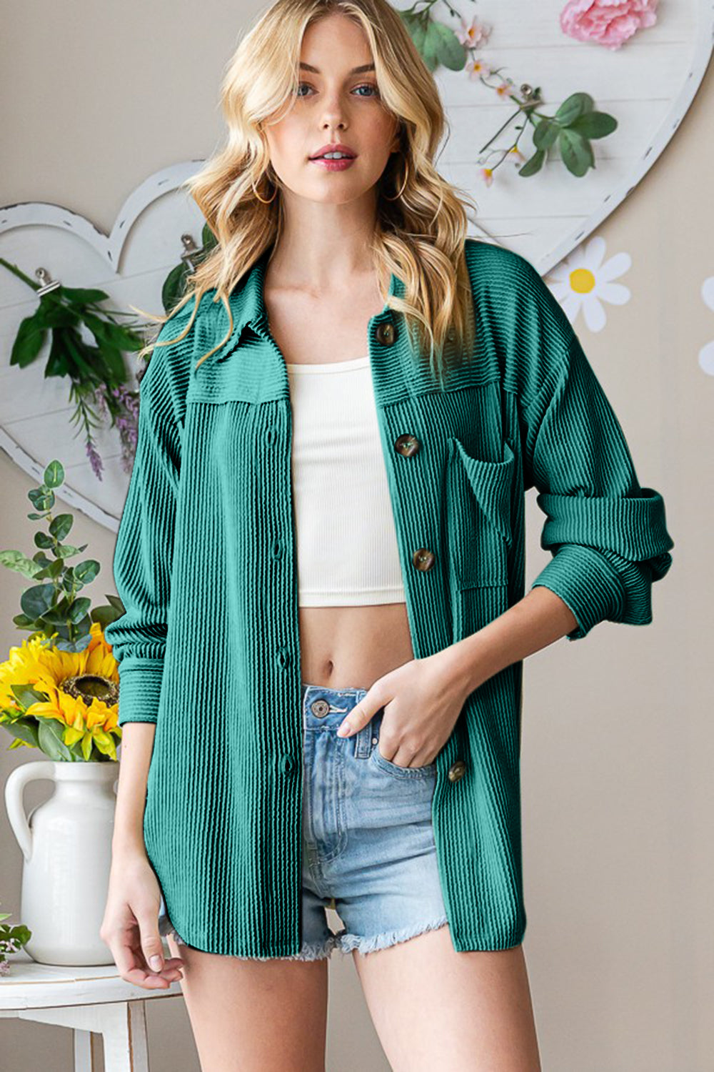 Woman wearing hunter green striped long sleeve button up shacket, styled with a white top and denim shorts.