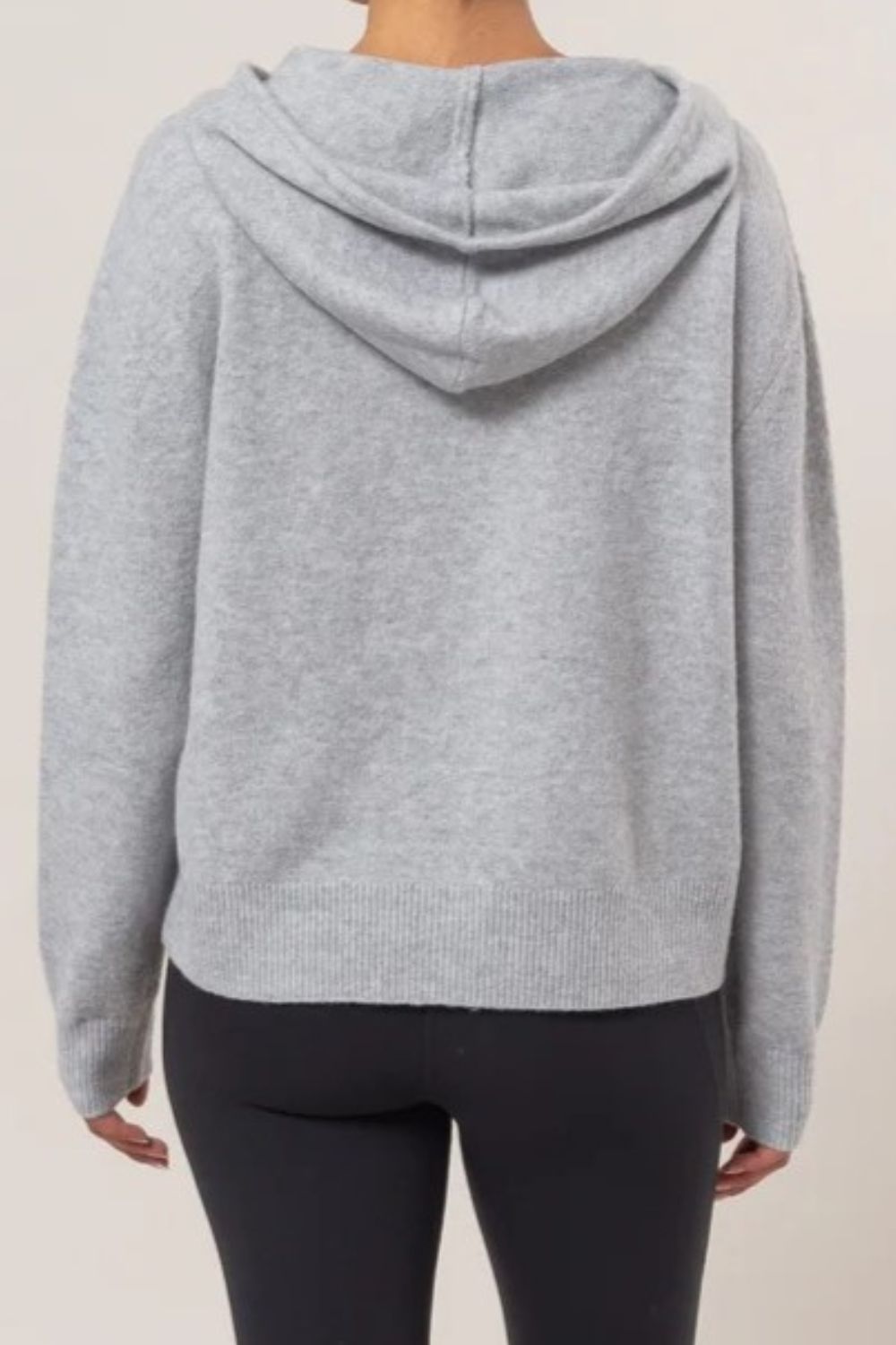 Woman wearing a gray HYFVE drawstring long sleeve hooded sweater, back view, showcasing casual style and cozy fabric.