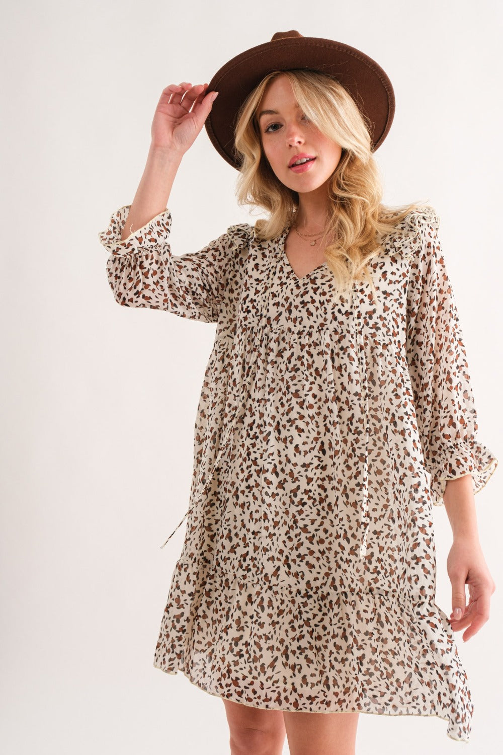 Woman wearing Ivory Leopard Ruffle Hem Woven Mini Dress with hat, showcasing ruffled and ruched details.