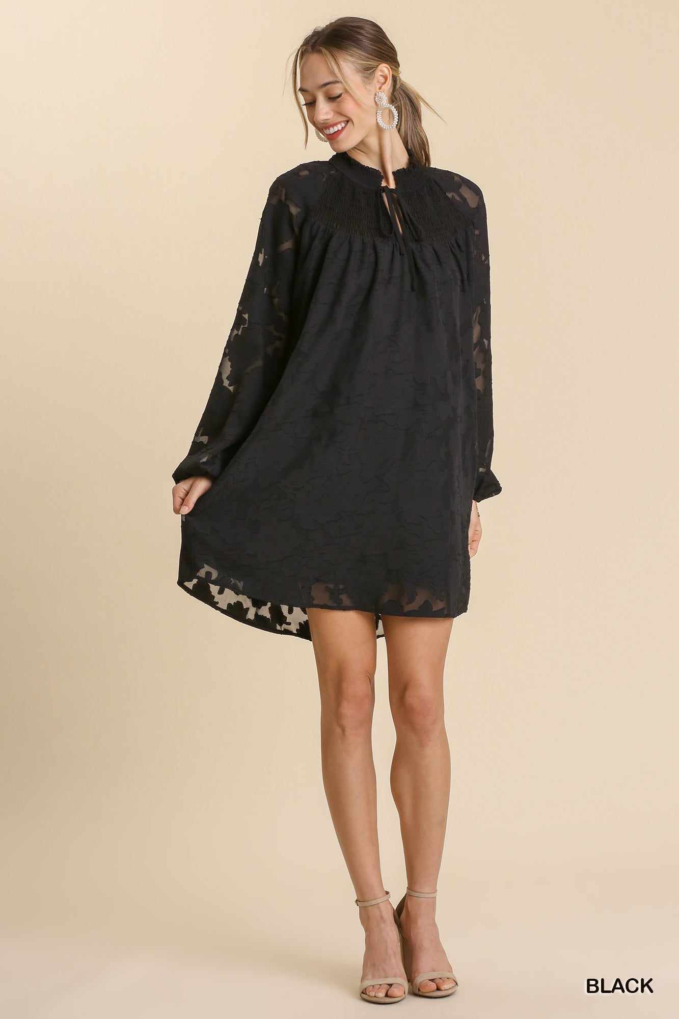 Woman wearing black jacquard tie neck yoke dress, long sleeves, smocked design, stylish outfit, available in sizes S, M, L.