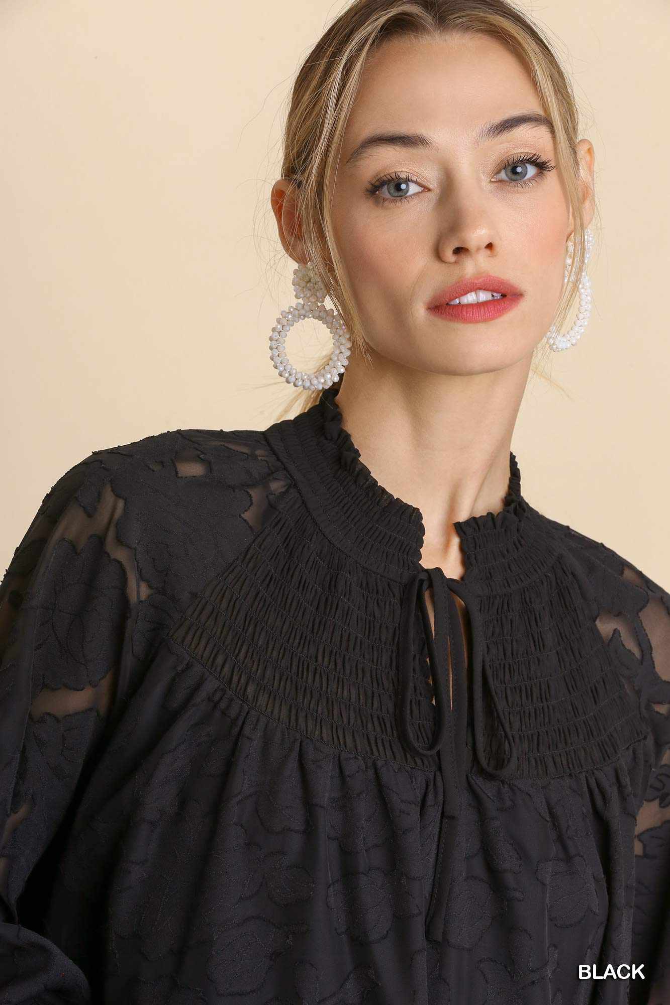 Woman wearing a black Jacquard Raglan Smocked Tie Neck Yoke Dress and hoop earrings.