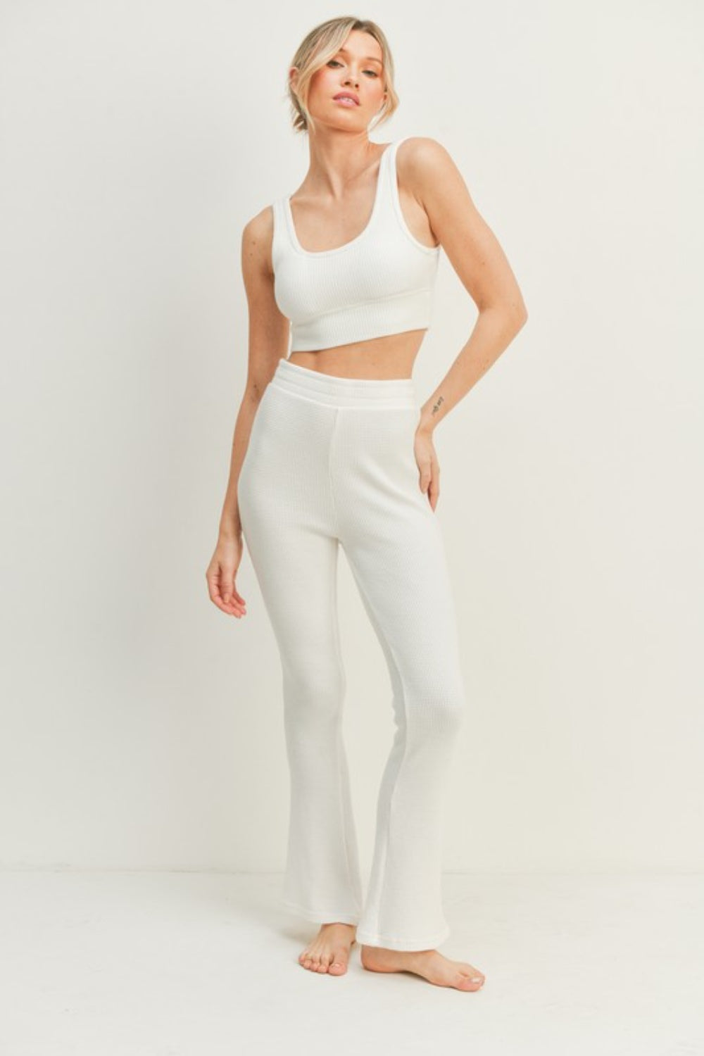 Woman wearing Kimberly C White Waffle Tank and High Waist Flare Pants Set, showcasing trendy and comfortable two-piece outfit.