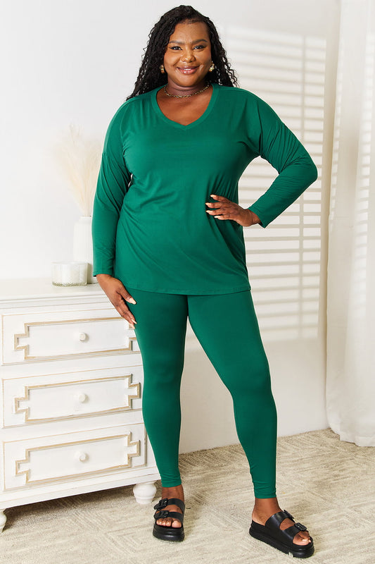 Woman wearing green Lazy Days full size long sleeve top and leggings set, styled with black sandals in a cozy room setting.