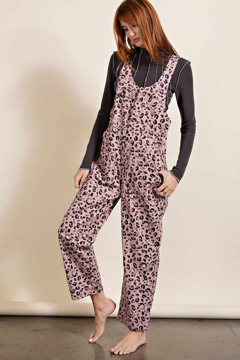 Woman wearing mauve leopard printed jumpsuit with U-neckline and racer-back style, featuring patch pockets and relaxed legs.