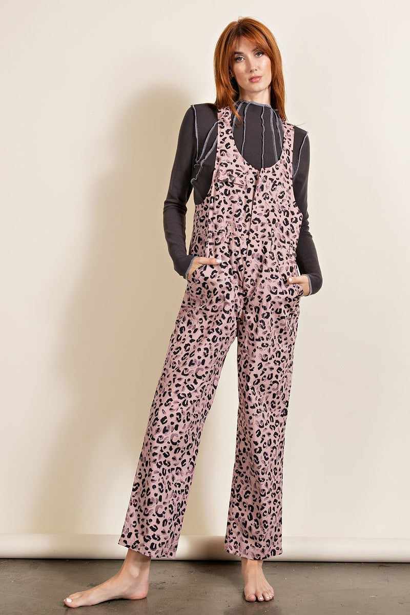 Woman wearing mauve leopard print jumpsuit with chest pockets, U-neckline, and racer-back style, crafted from 100% cotton.