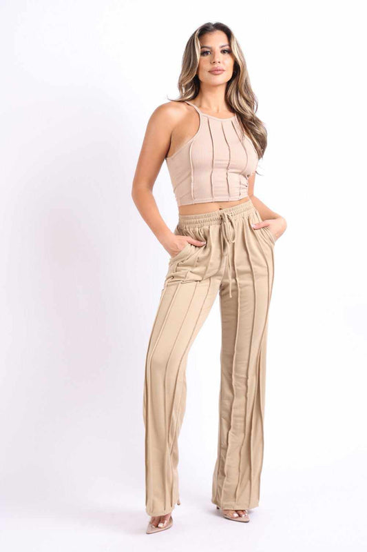 Woman wearing mocha pin tuck detailed lounge set with tank top and pants, made of rayon, polyester, and spandex.