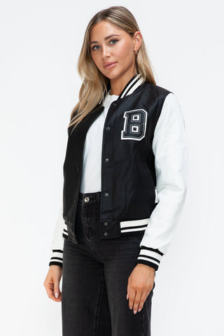 Woman wearing a Love PU Leather Contrast Snap Down Bomber Jacket with black and white design and letter embellishment.