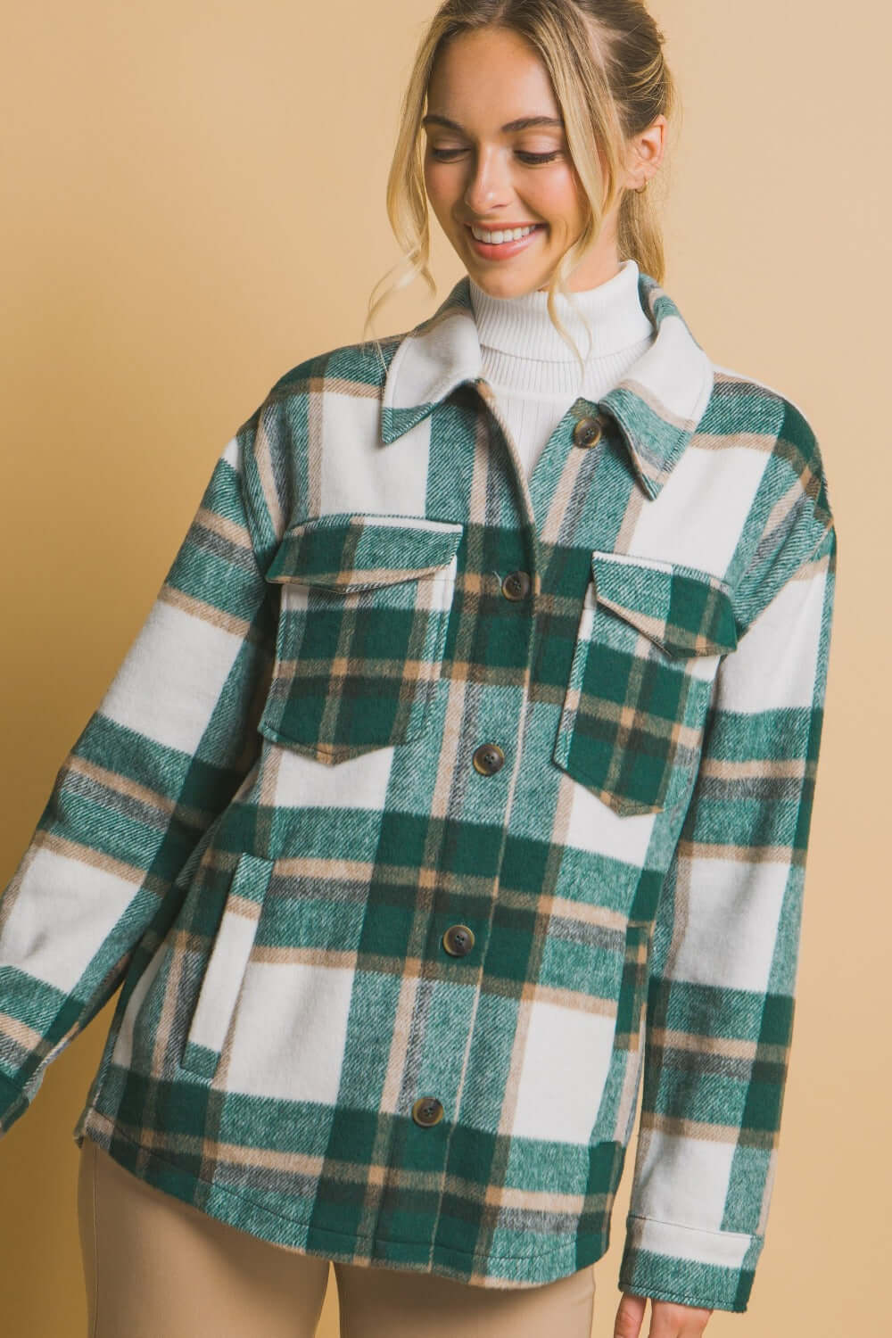 Woman wearing a green plaid button-up shacket with pockets, made from 100% polyester, showcasing a stylish and comfortable look.