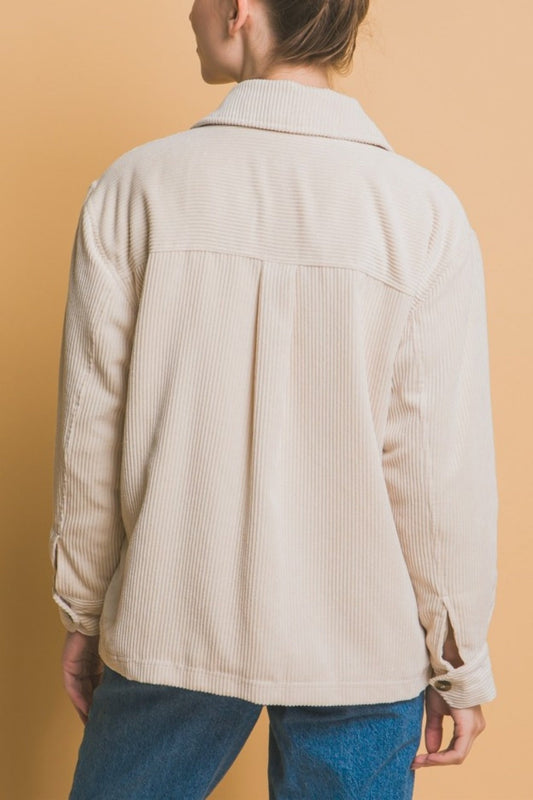 Beige corduroy button-up jacket with sherpa lining, back view, styled with blue jeans against a beige background.