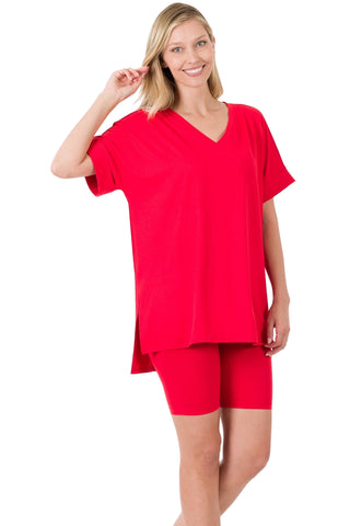 Woman wearing a red brushed microfiber V-neck top with hi-low hem and matching biker shorts, showcasing a comfortable and stylish fit.