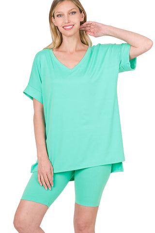Woman wearing mint green V-neck brushed microfiber top and biker shorts set with hi-low hem, showcasing soft and stretchy fabric.