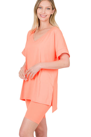 Neon coral V-neck top and biker shorts set, brushed microfiber, featuring a hi-low hem, modeled for perfect stretch and comfort.
