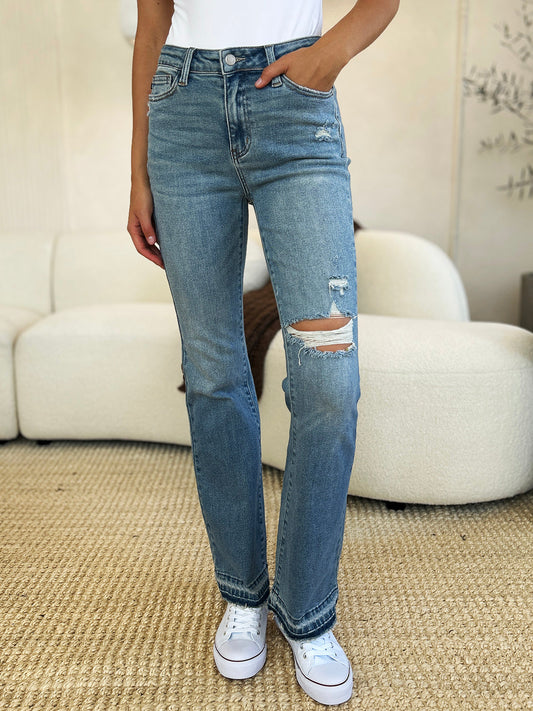 Woman wearing mid-rise distressed jeans with destroyed hem and moderate stretch, featuring basic style and ripped knee detail.