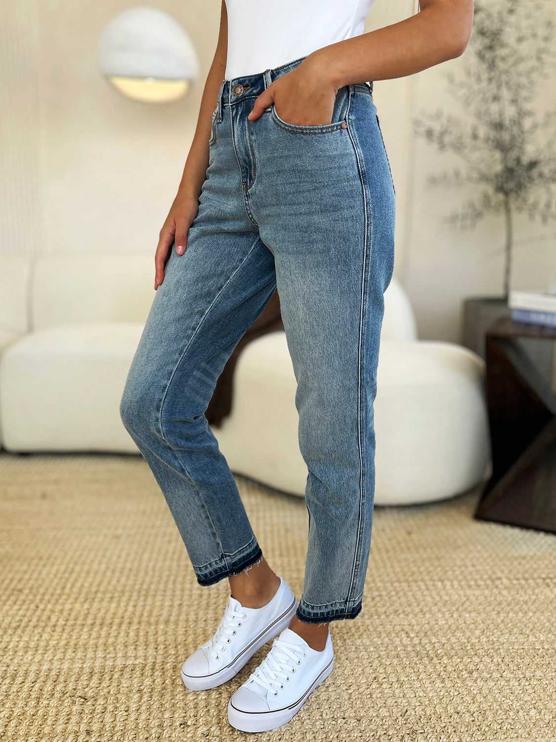 Woman wearing mid rise rigid magic release hem jeans with moderate stretch, featuring a comfortable fit and stylish design.