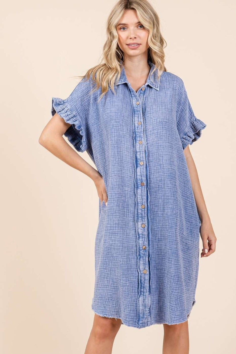 Woman wearing blue mineral wash cotton gauze mini shirt dress with buttons, ruffled sleeves, and raw hem.