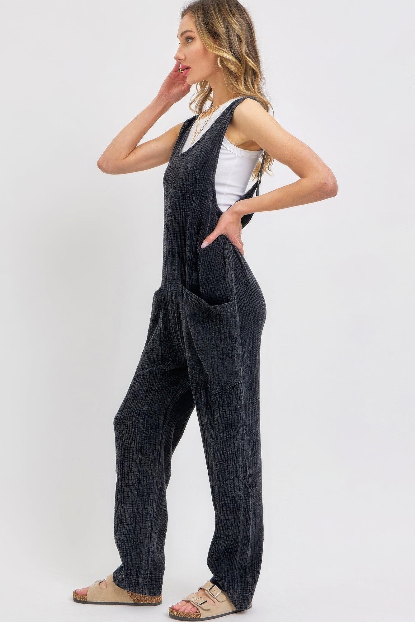 Woman wearing black mineral-washed summer jumpsuit with adjustable straps and patch pockets.