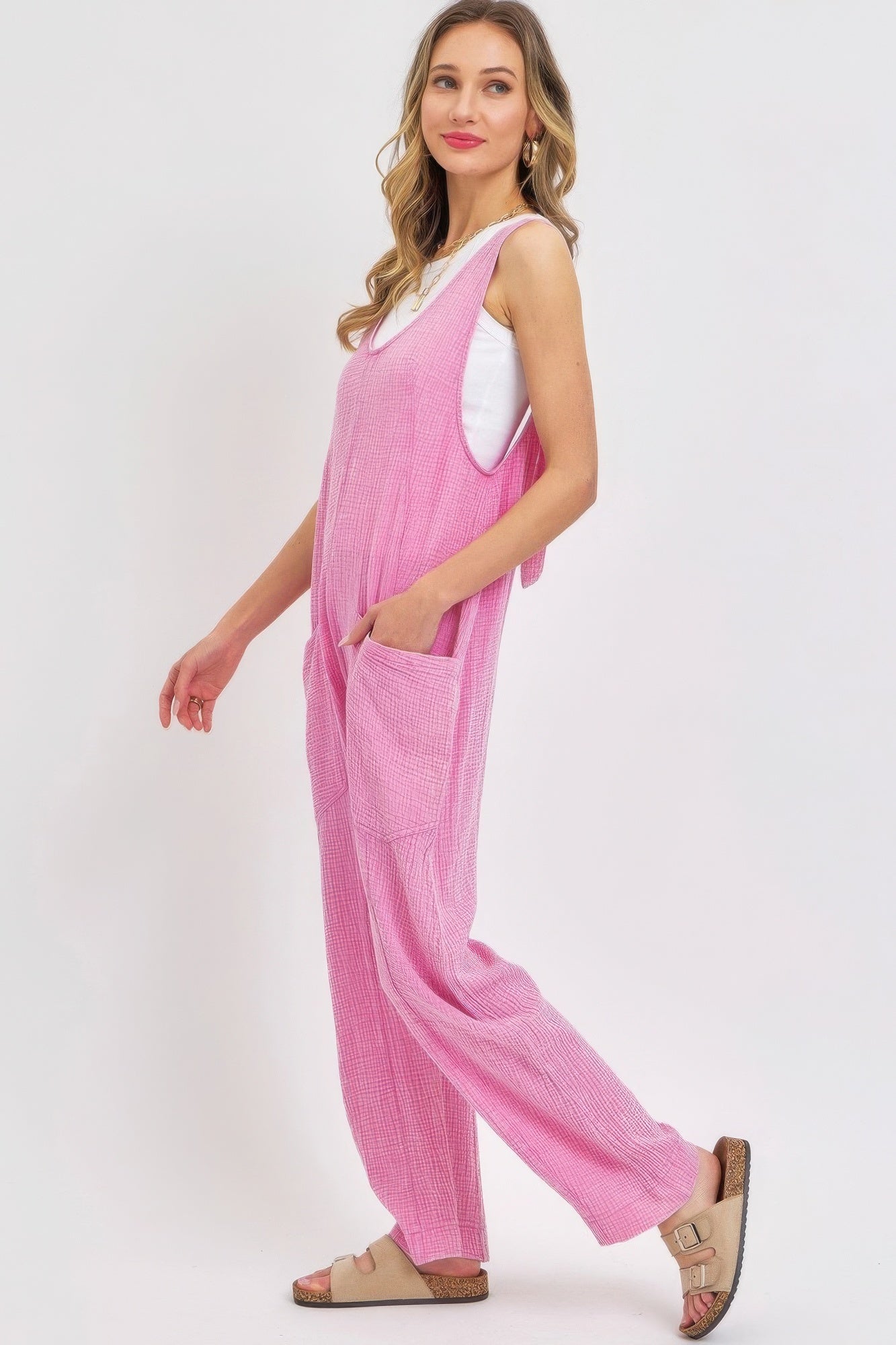 Woman wearing pink mineral washed summer jumpsuit with adjustable straps and oversized pockets, showcasing relaxed, effortless style.