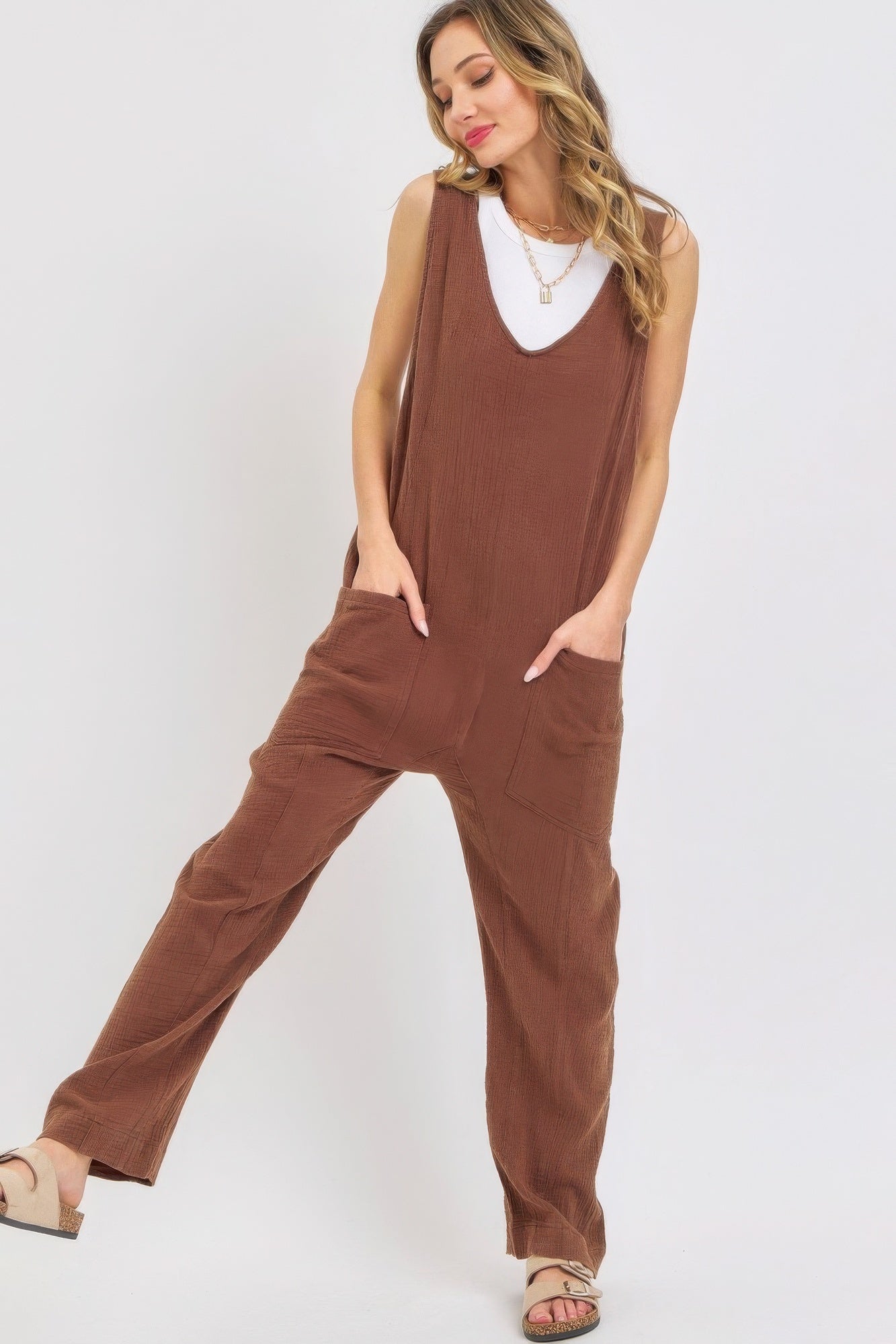 Woman wearing a brown mineral washed summer jumpsuit with oversized pockets and adjustable straps, exuding relaxed and effortless style.