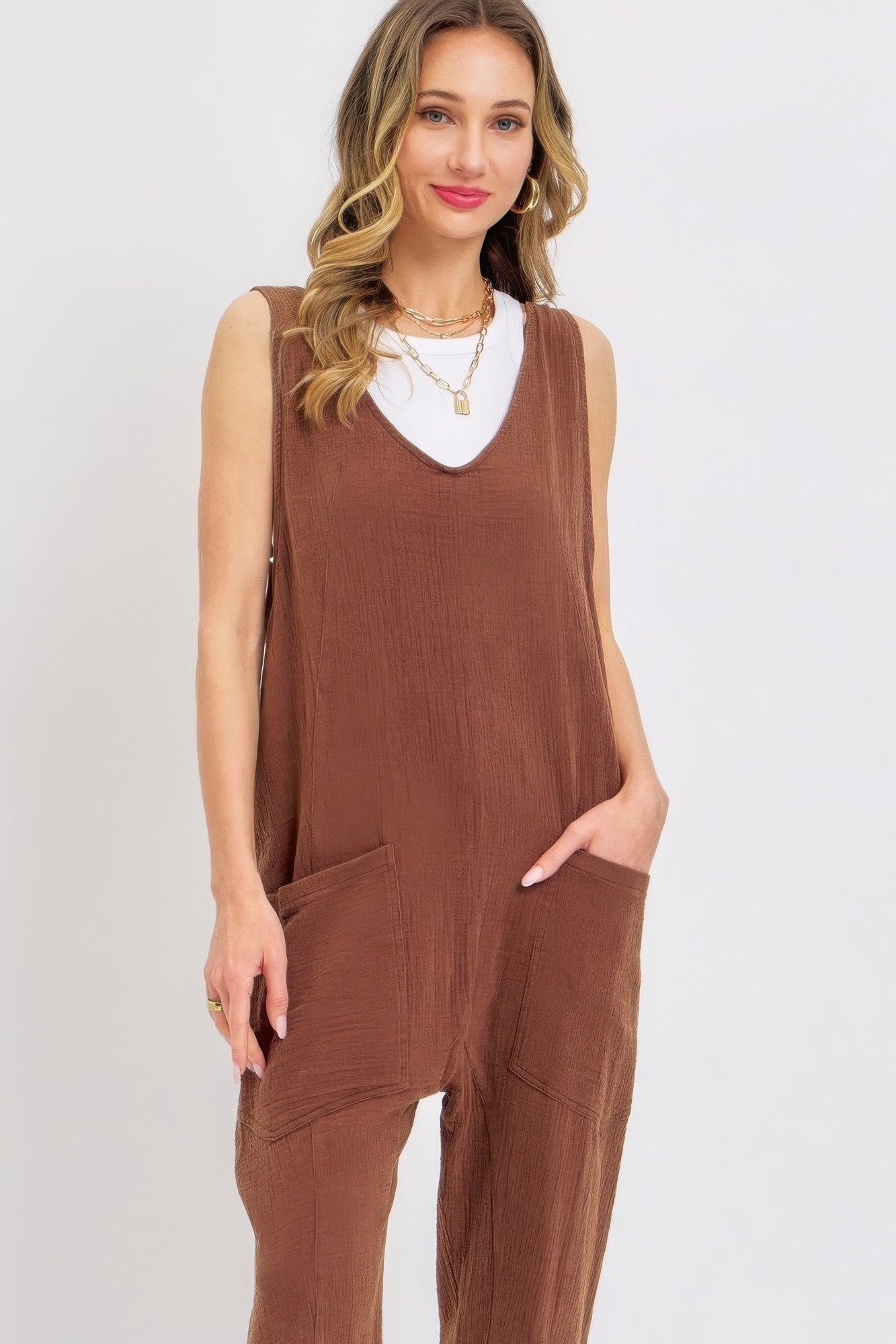 Woman wearing brown mineral washed summer jumpsuit with oversized pockets and adjustable straps.