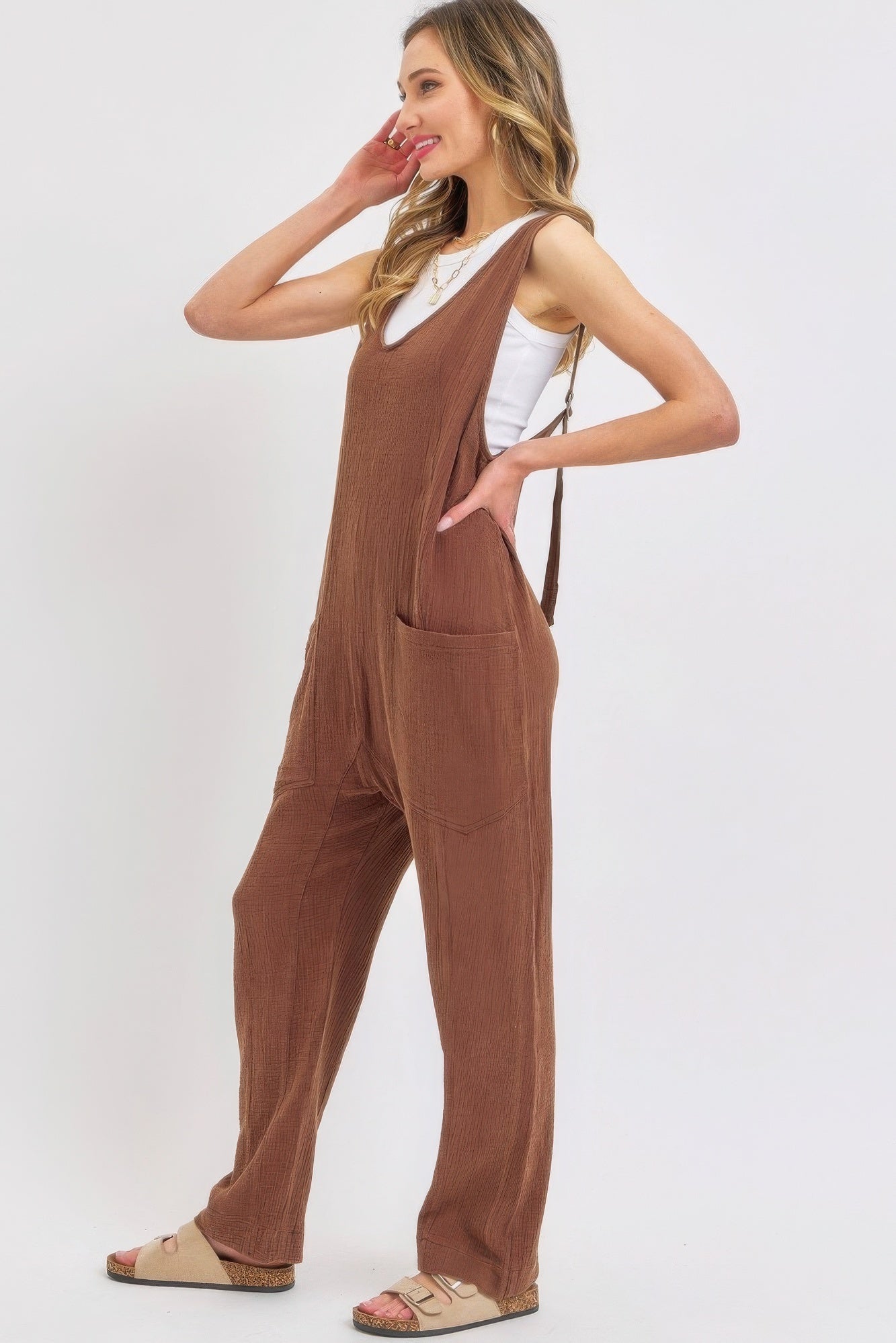 Woman wearing a mineral washed summer jumpsuit with adjustable straps and oversized pockets, showcasing effortless and relaxed style