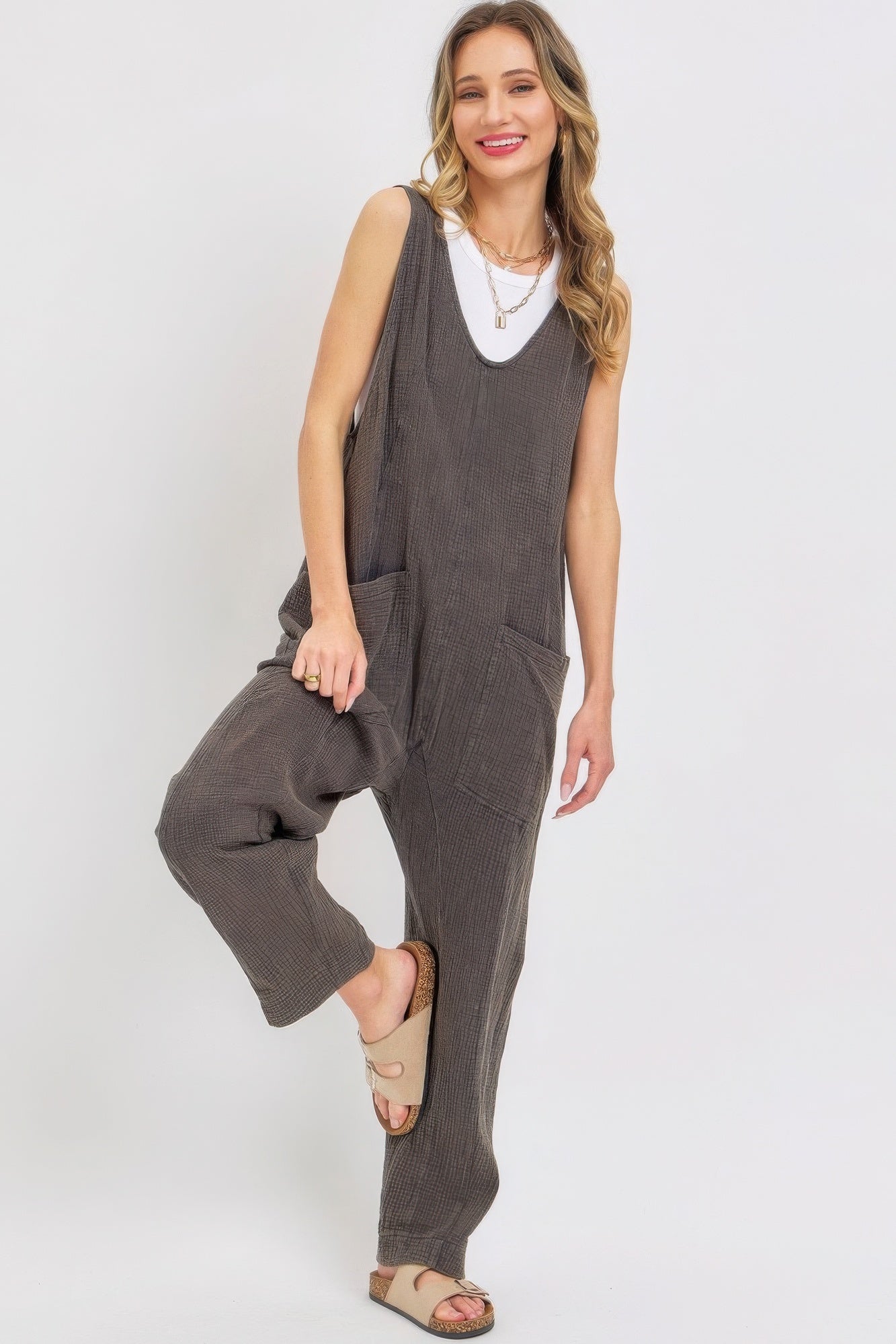 Woman wearing a mineral washed summer jumpsuit with oversized pockets and adjustable straps, showcasing casual and relaxed style.