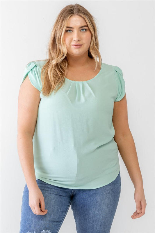 Plus size woman wearing mint textured short sleeve blouse with cap sleeves and crew neckline, paired with jeans.