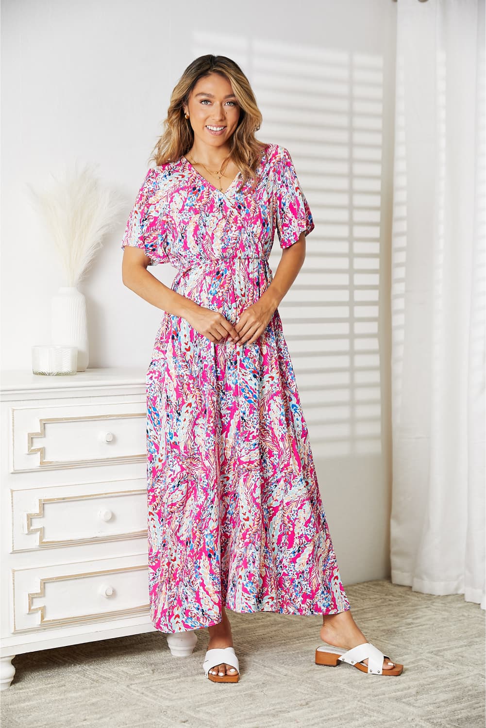 Woman wearing vibrant multicolored V-neck maxi dress with short sleeves, perfect for summer events or vacations.