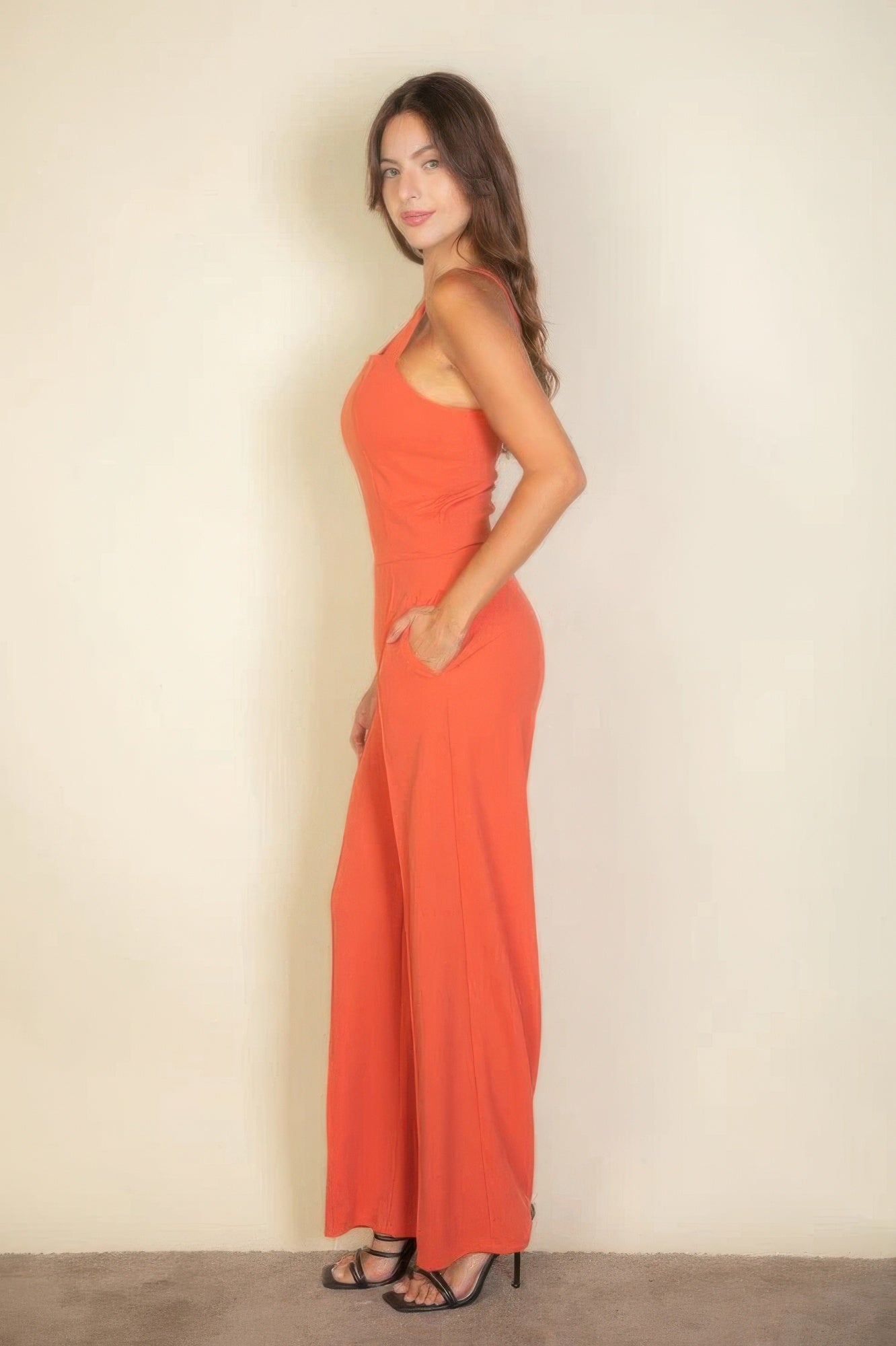 Woman wearing an orange notched neck cami jumpsuit with a sleek, flattering fit.