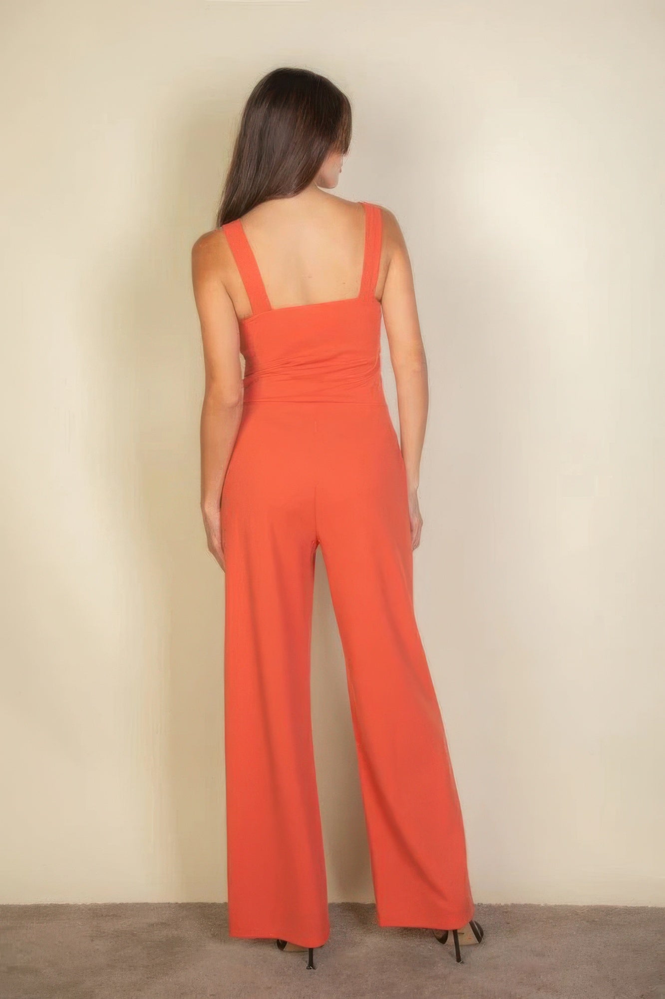 Back view of woman wearing orange Notched Neck Cami Jumpsuit with wide straps, showcasing sleek and flattering fit.