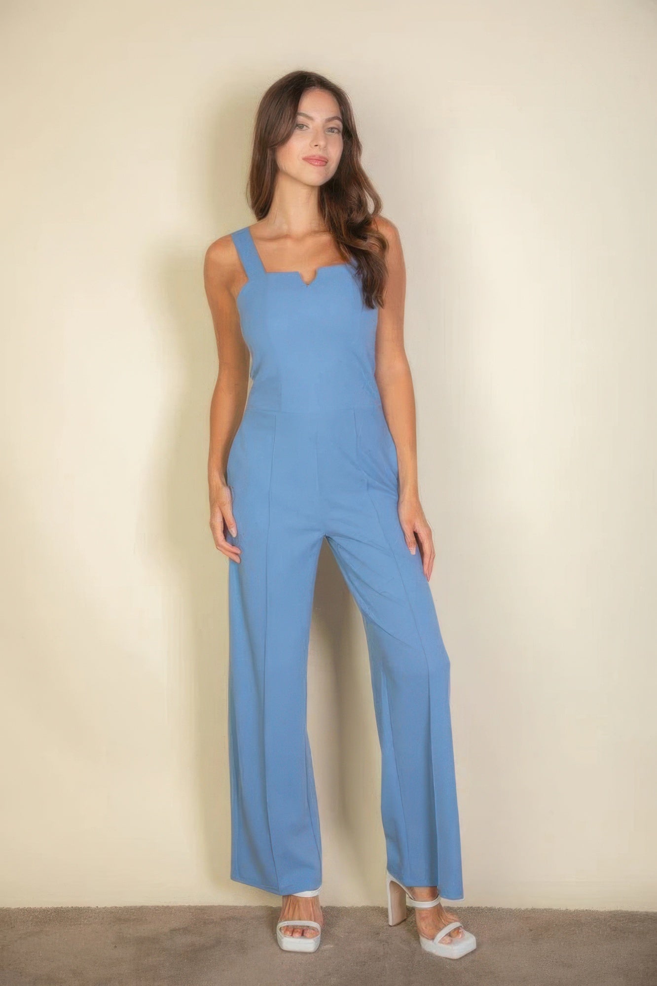 Woman wearing a blue notched neck cami jumpsuit, showcasing a sleek and flattering fit.