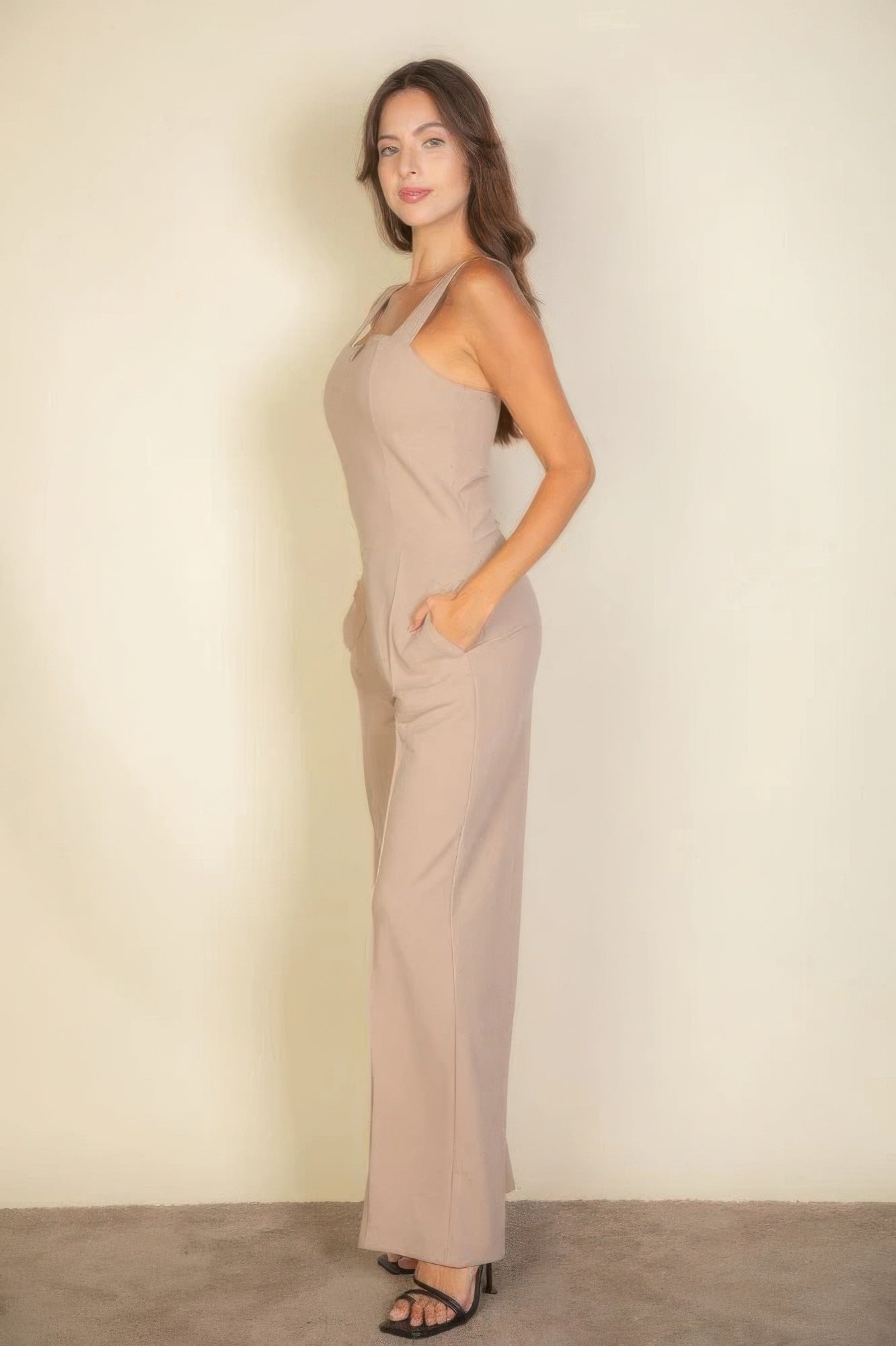 Woman wearing taupe notched neck cami jumpsuit, highlighting chic and flattering fit in a soft, stretchy fabric.