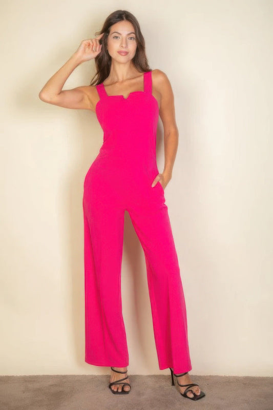 Woman wearing a vibrant pink notched neck cami jumpsuit with pockets, showcasing a modern chic style, perfect for day to night wear.