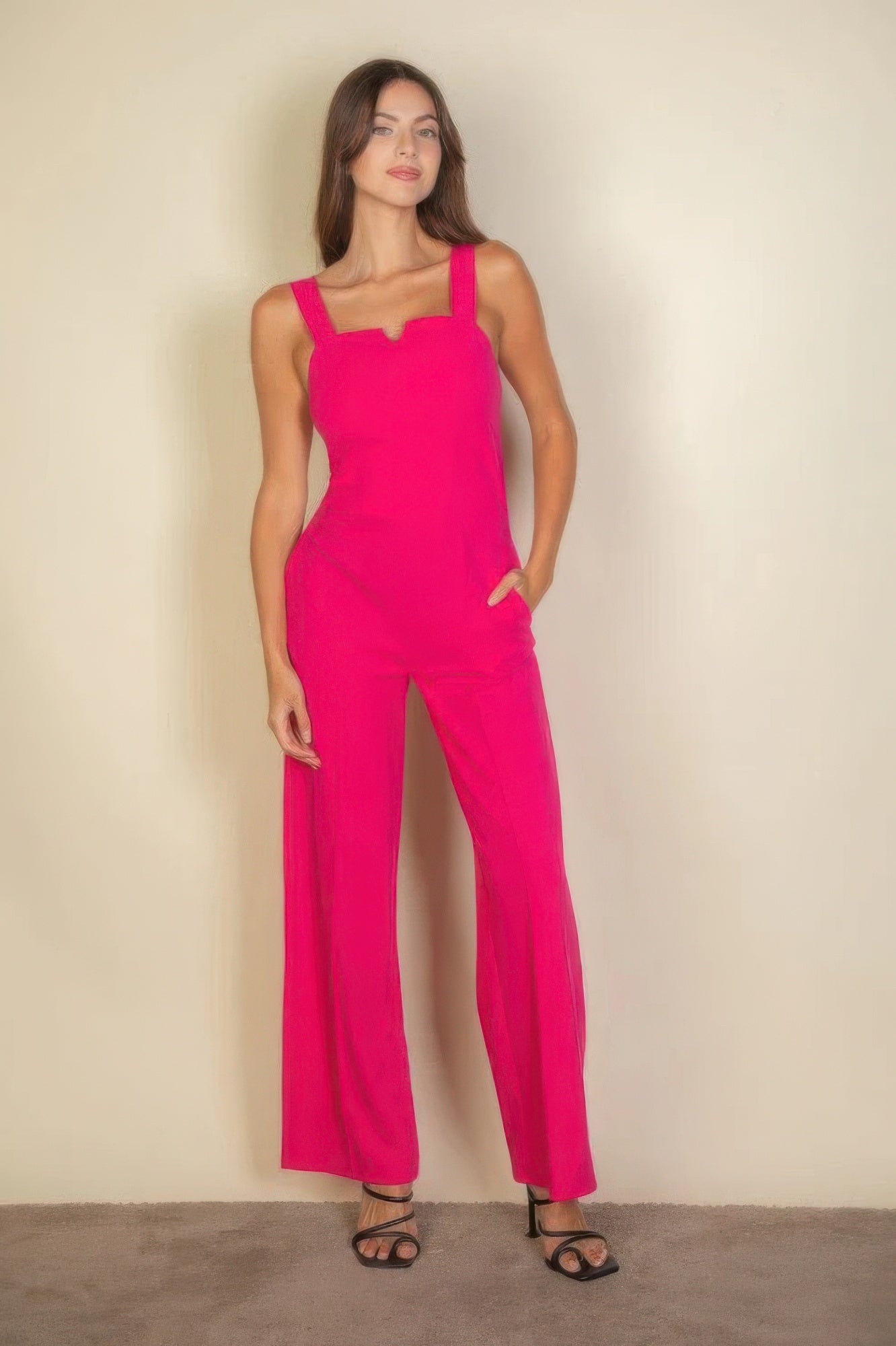 Woman wearing a bright pink notched neck cami jumpsuit with flattering fit and trendy design.