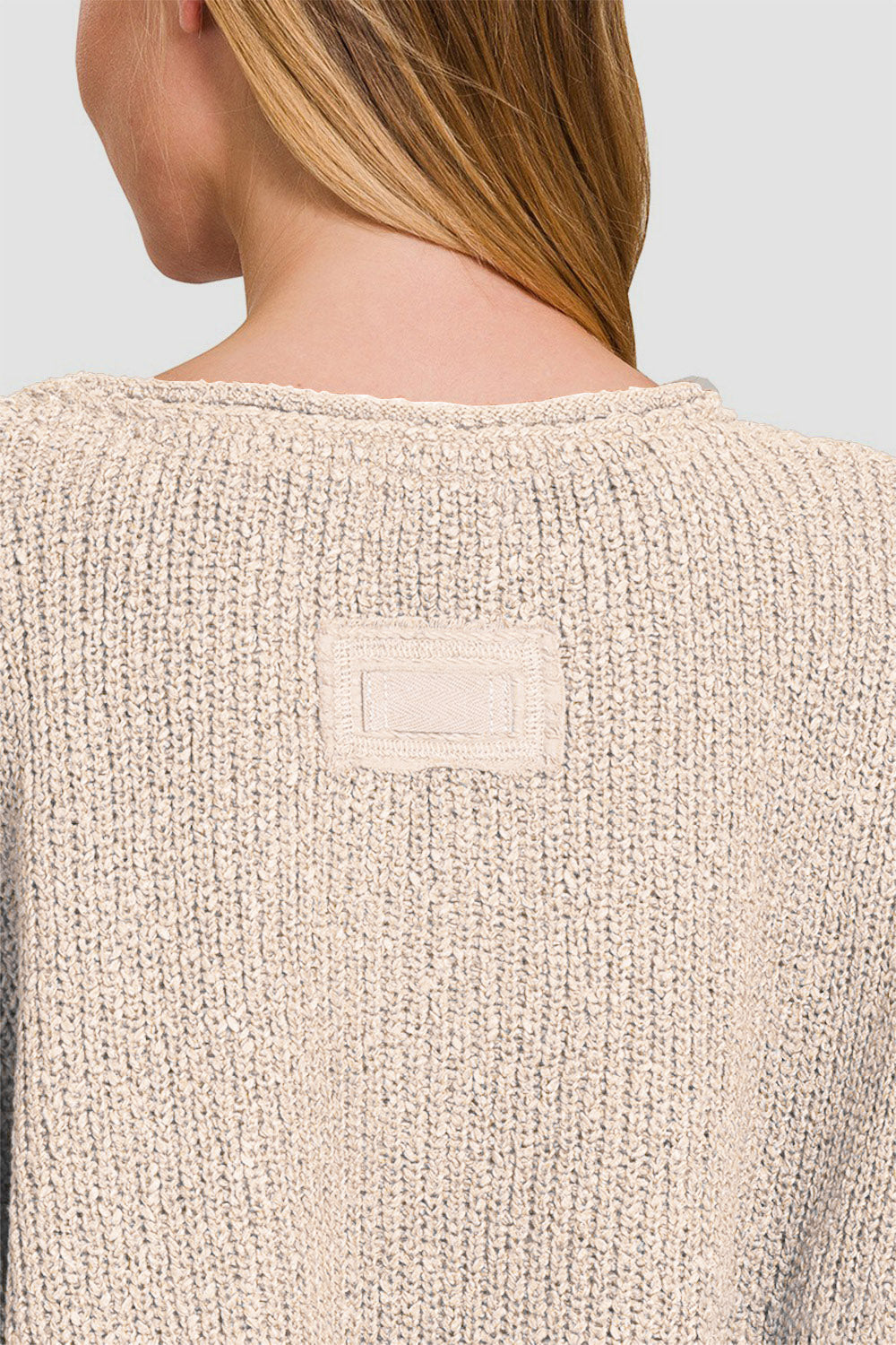 Back view of notched side slit patch sweater showcasing knit texture and patch detail in neutral color.